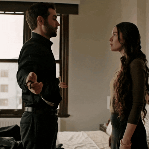 a man in a black shirt is holding a rosary and talking to a woman