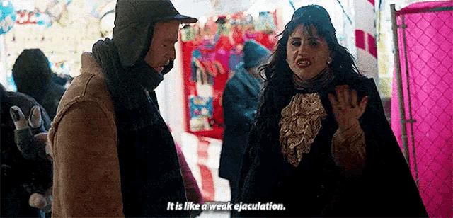 a man and a woman are standing next to each other at a carnival and the woman is talking to the man .