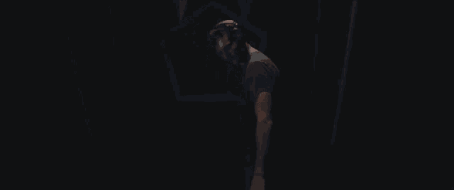 a man wearing a virtual reality headset is walking through a dark tunnel .