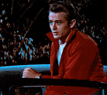 a man wearing a red jacket and white shirt is sitting in a car