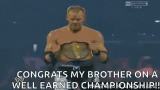 a man is holding a wrestling championship belt in a ring .