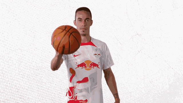 a man in a red bull shirt is holding a basketball in his hand