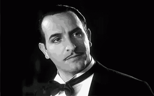 a man wearing a tuxedo and bow tie is smiling