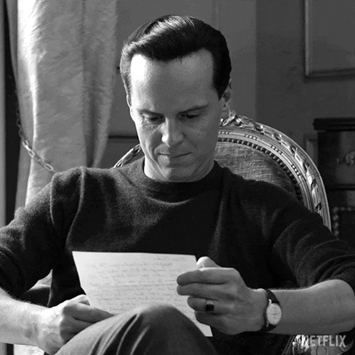 a man sits in a chair reading a letter with a netflix logo behind him