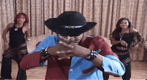 a man in a cowboy hat is dancing with two women