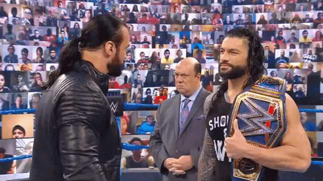 roman reigns is holding a wrestling championship belt while talking to another wrestler