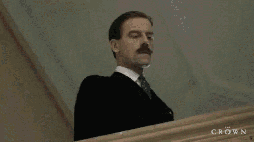 a man in a suit and tie is standing on a set of stairs looking down .