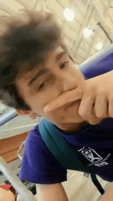 a young man wearing a purple shirt with the letter x on the front
