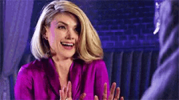 a woman in a purple shirt is smiling while sitting at a table with a man .