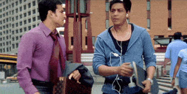 a man in a purple shirt and tie is talking to another man in a blue jacket