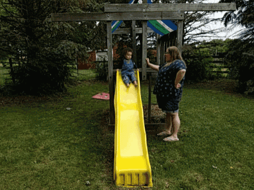 a woman watches a child on a yellow slide that says 111
