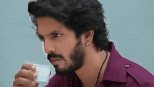 a man with a beard is drinking a cup of tea .