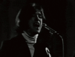a black and white photo of a man singing into a microphone in a dark room