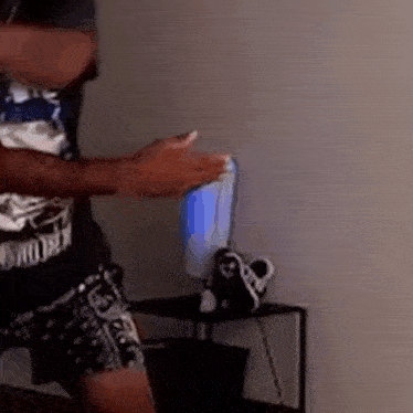 a man is standing in a room holding a can of soda and a remote control .