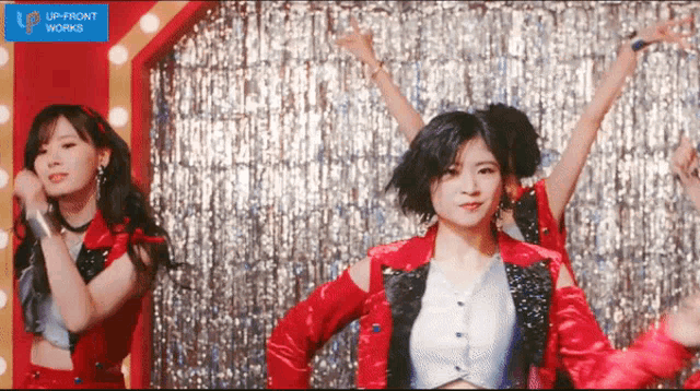 a girl in a red jacket is dancing in front of a sign that says up front works