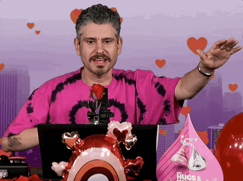 a man in a pink shirt stands in front of a laptop