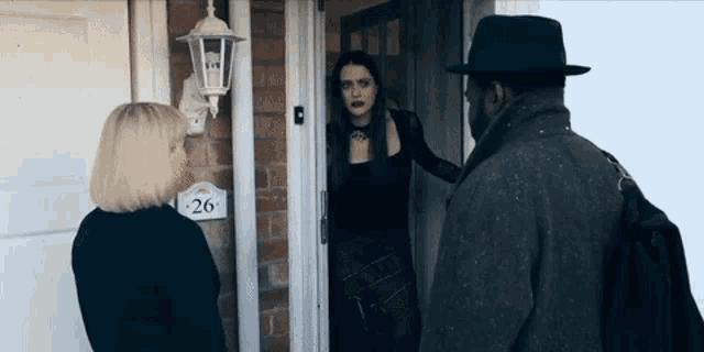 a woman standing in front of a door with a sign that says 26 on it
