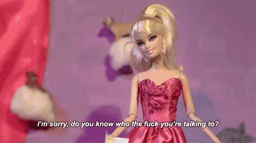 a barbie doll is wearing a pink dress and talking to a person .