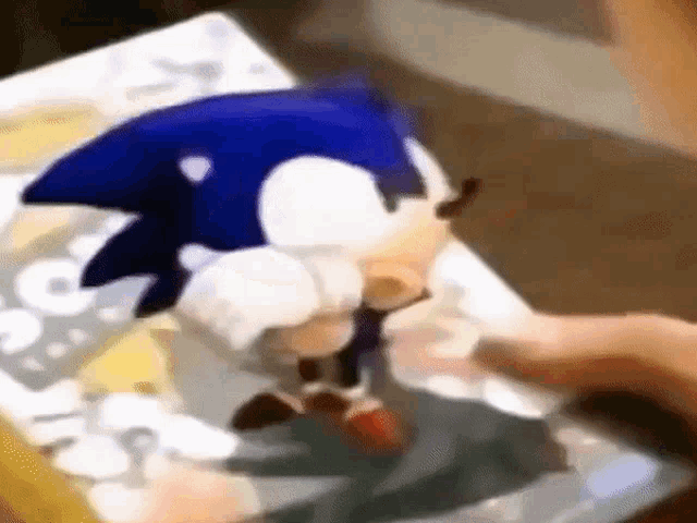a close up of a person holding a sonic the hedgehog toy on a table .