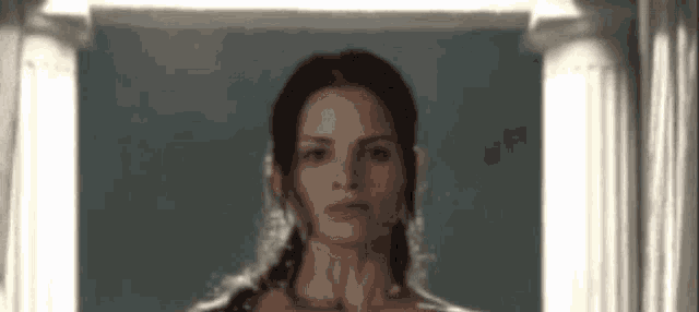 a woman is standing in front of a pillar in a room .