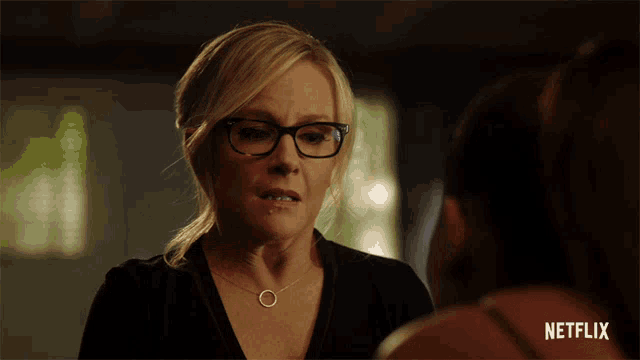 a woman with glasses and a necklace is talking to another woman with a netflix logo in the corner