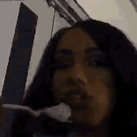 a close up of a woman 's face in a dark room eating a piece of food .