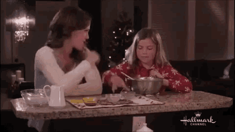 a woman and a little girl are sitting at a table with a bowl of food on it .