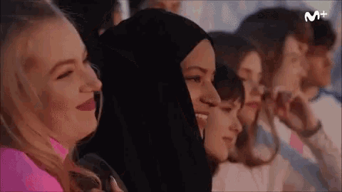 a group of women are sitting in a row and one of them is wearing a hijab ..