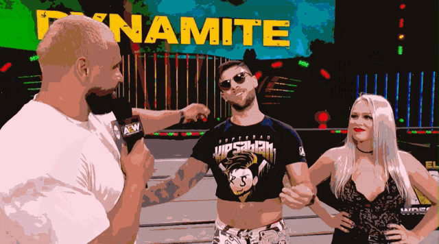a man wearing a dynamite shirt is talking to a woman