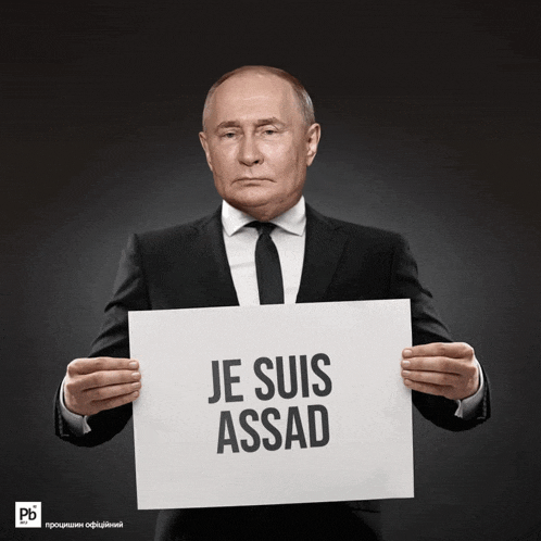 a man in a suit and tie is holding a sign that says je suis assad