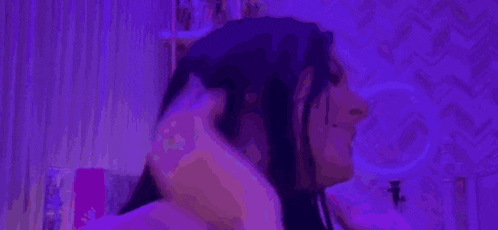 a woman with long black hair is laying on a bed in a room with purple lights .