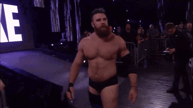 a man with a beard is walking into a wrestling ring with a sign that says jae