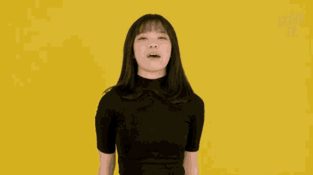 a woman in a black shirt is dancing in front of a yellow background with jt48 written on it