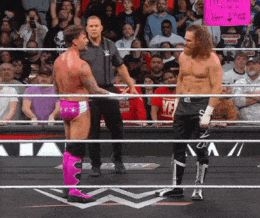 two wrestlers are standing in a ring with a sign that says " i 'm a fan "