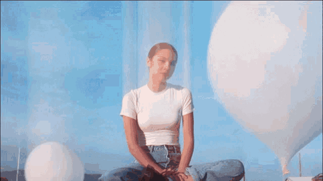 a woman in a white t-shirt is smiling and looking at the camera .
