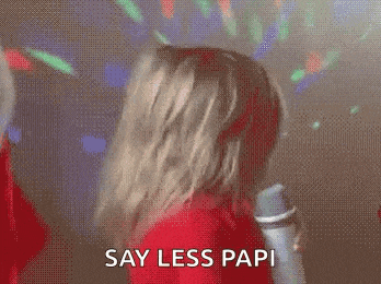 a woman in a red dress is holding a microphone and saying say less papi