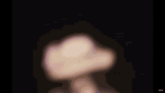 a blurry picture of a person wearing a hat in a dark room .