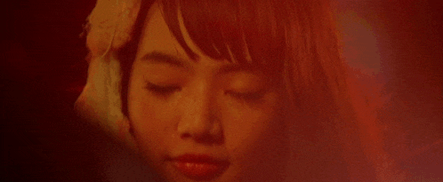 a close up of a woman 's face in a dark room looking at the camera .
