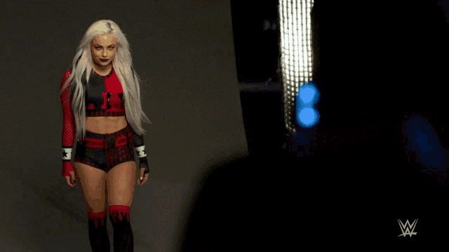 a woman in a red and black outfit is walking in front of a w logo