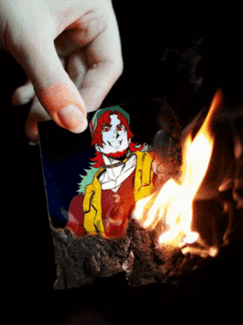 a person is burning a picture of a man with red hair and green hair