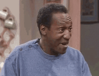 a man in a blue shirt is making a funny face while standing in a room .