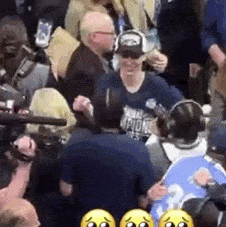 a group of people are standing in a crowd and a man is standing in the middle of the crowd .