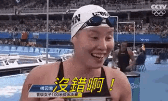 a woman wearing a swim cap and goggles is smiling in front of a crowd at a swimming pool .