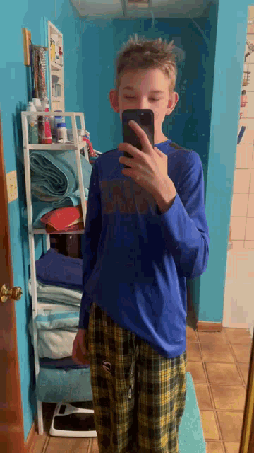 a young boy taking a selfie in a bathroom
