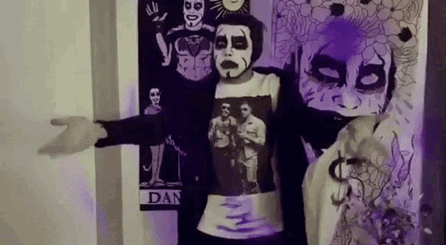 a person wearing a mask and a t-shirt is standing in front of a wall with a painting on it .