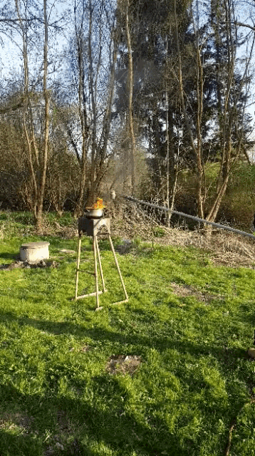 a wooden stool sits in the middle of a grassy field with trees in the background