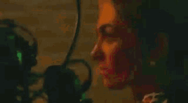 a close up of a woman 's face in a dark room with a green light behind her .