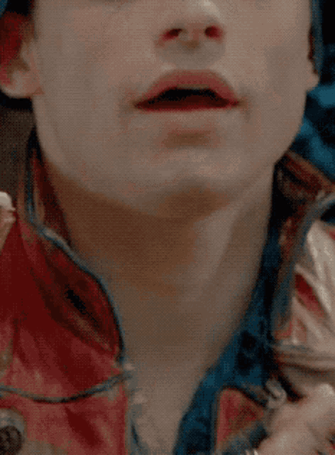 a close up of a man 's face with a red jacket on