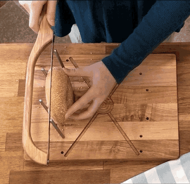 a person is cutting a loaf of bread on a wooden cutting board