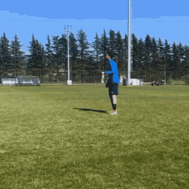 a man in a blue shirt is standing on a field